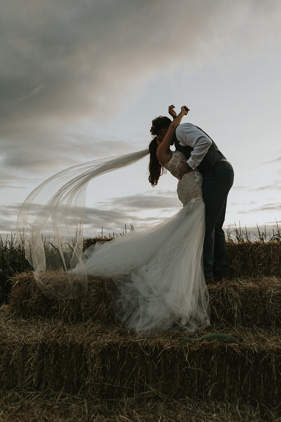 boho wedding south wales - Bride and Groom on bale of hay